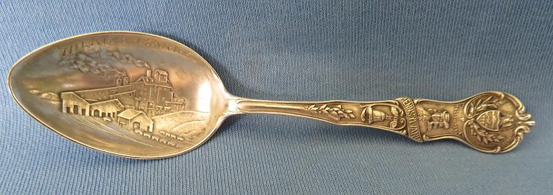 Souvenir Mining Spoon Wilkes-Barre.JPG - SOUVENIR MINING SPOON WILKES-BARRE PA - Sterling silver souvenir demitassespoon, 4 in. long, bowl engraved with colliery buildings and marked WILKES-BARRE, handle marked with image of William Penn and Liberty Bell with Pennsylvania, reverse marked Sterling and maker’s mark of Mechanics Sterling Co. (Attleboro, MA 1896 - ?), reverse handle marked with pick and shovel along with state seal  [Wilkes-Barre is in the center of the Wyoming Valley anthracite coal region in northeastern Pennsylvania.  Founded in 1769, it was originally named Wyoming but renamed later in honor of two British members of parliament, John Wilkes and Col. Issac Barre, who defended the American colonies in parliamentary debates.  In 1818, Wilkes-Barre was incorporated as a borough, with a city charter following in 1871.  Coal mining was the most important element of the city’s economy.   Hundreds of thousands of immigrants flocked to the city; they were seeking jobs in the numerous mines and collieries that sprang up.  Wilkes-Barre’s population exploded as the city became a center of supply to support these mines.  In 1914 employment at the anthracite mines reached a maximum of 180,000 workers.  Anthracite production peaked in 1917 at over 100 million tons with 776 mines in operation.  The anthracite industry went into steady decline after World War I.  The primary reason was competition from abundant supplies of lower cost oil and gas.  A large drop in anthracite production occurred during the Depression with only a small bounce-back during World War II.  The earlier downward trend continued after the War.  In 1959, The Knox Mine near Wilkes-Barre broke through the bottom of the Susquehanna River, flooding the underground mines and ending deep coal  production in the area.]